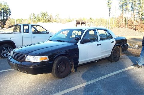 2001 Ford Crown Victoria - A two-tone sedan is parked next to a white pickup truck on a sunny day.