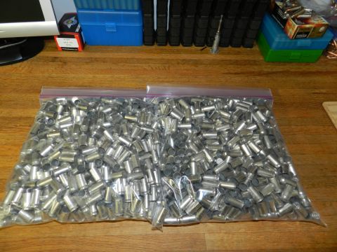 1996 Ford Bronco - A large quantity of spent shell casings fills two plastic bags, resting on a wooden table alongside ammunition boxes and a computer monitor.
