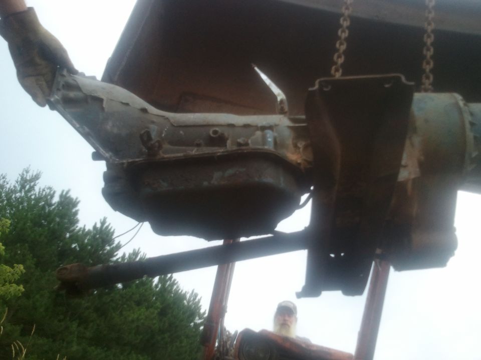 transmission being lifted by chains, driveshaft visible