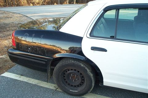 2001 Ford Crown Victoria - Rear quarter panel of a black and white police car, showing "EMERGENCY" text.