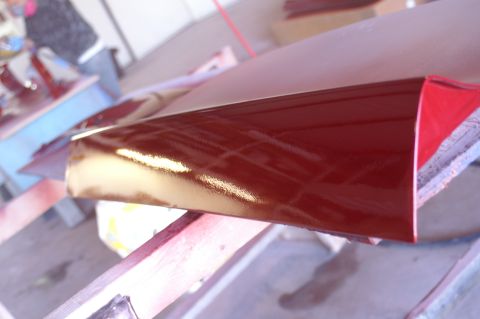 1970 Ford Mustang - A red car part with a shiny finish is shown, possibly undergoing restoration or painting.