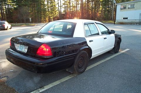 2001 Ford Crown Victoria - A two-tone police car is parked in a lot, with a second police car visible in the distance.