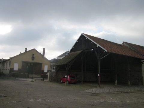 1991 Ford LTD Crown Victoria - A red hatchback is parked under a large wooden barn structure.