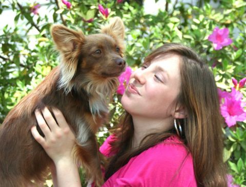 1976 Ford Ranchero - A woman smiles while holding a small brown dog in front of blooming pink flowers.