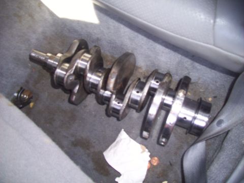 1995 Ford Probe - A crankshaft is shown resting on the floor of a vehicle's interior.