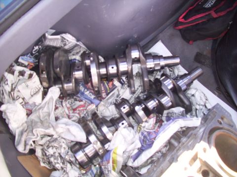 1995 Ford Probe - Multiple crankshafts are visible, wrapped in newspaper and stored in a vehicle's cargo area.