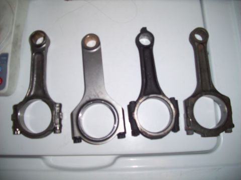 1995 Ford Probe - Four engine connecting rods are shown on a white surface.