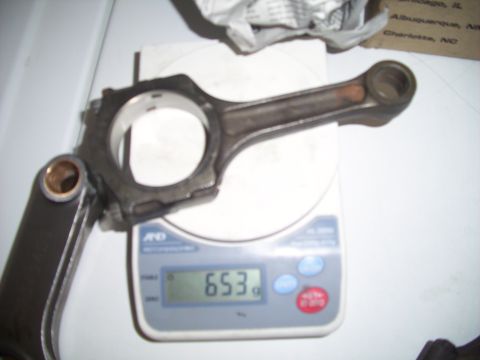 1995 Ford Probe - A single engine connecting rod is weighed on a digital scale, displaying 653 grams.