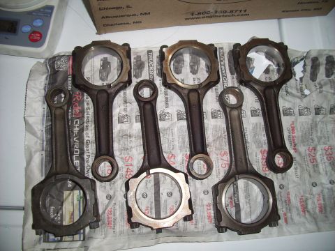 1995 Ford Probe - A collection of engine connecting rods are displayed on a surface covered with newspaper advertisements.
