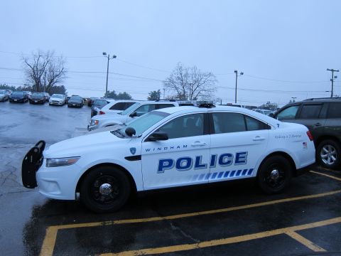 1991 Ford LTD Crown Victoria - A white police car is parked in a lot with other vehicles visible in the background.