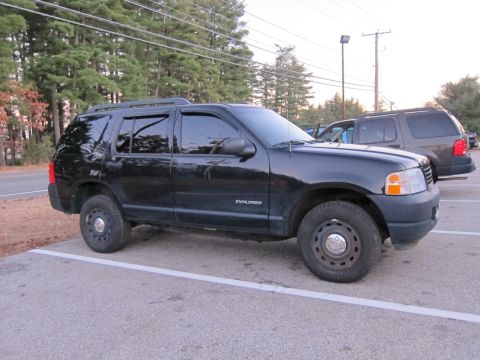 1991 Ford LTD Crown Victoria - A black SUV is parked in a lot next to another vehicle.