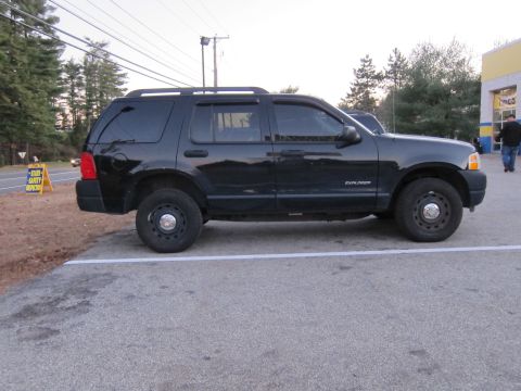 1991 Ford LTD Crown Victoria - This black Ford Explorer SUV is parked in a lot next to a road.