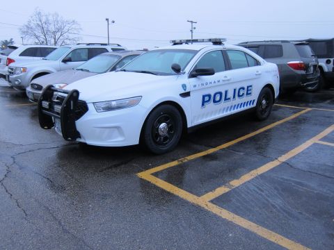 1991 Ford LTD Crown Victoria - A white police car is parked in a lot with other vehicles.