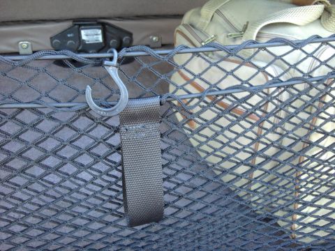 1994 Ford Bronco - Close-up inside a cargo area showing a gray elastic cargo net stretched across the space, with a metal S-hook on a webbing strap clipped ov…