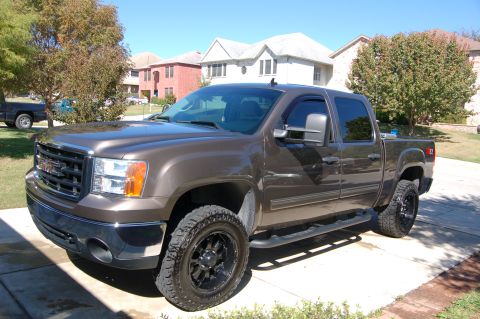 2007 GMC Sierra 1500 - A brown 2007 GMC Sierra 1500 pickup truck is parked in a driveway on a sunny day.