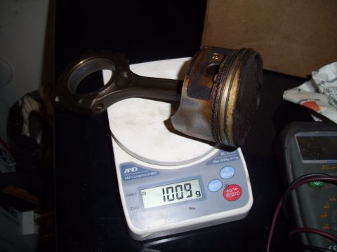 1995 Ford Probe - A piston and connecting rod assembly is weighed on a digital scale.