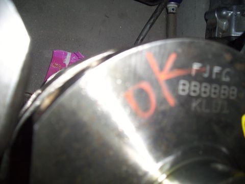 1995 Ford Probe - Close-up of a mechanical part with orange markings and stamped alphanumeric codes, possibly from an engine assembly.