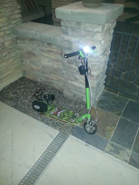 1978 Ford Bronco - A green motorized scooter with cartoon graphics and illuminated headlights is parked near a stone pillar.