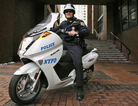 1991 Ford LTD Crown Victoria - NYPD officer on a white electric scooter parked outside a building.