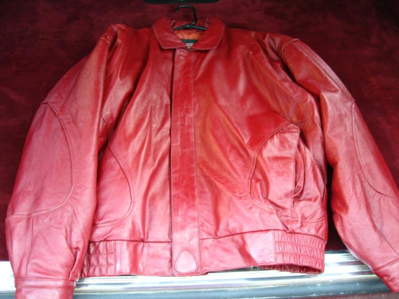 Red leather jacket with pockets and elastic cuffs, hanging on a hanger