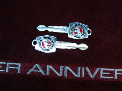 1994 Ford Bronco - Two keys with Ford Bronco emblems are shown on a dark fabric with embroidered text.