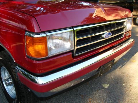 1994 Ford Bronco - Close-up of the front grille and headlights of a red Ford F-Series truck.