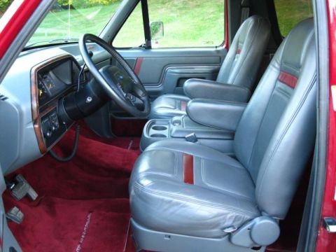 1994 Ford Bronco - The interior of a Ford Bronco features gray leather seats with red trim and plush red carpeting.