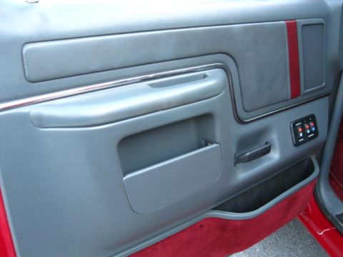 1994 Ford Bronco - Interior of a 1992 Ford Bronco, showing the driver's side door panel with red accents and a storage pocket.