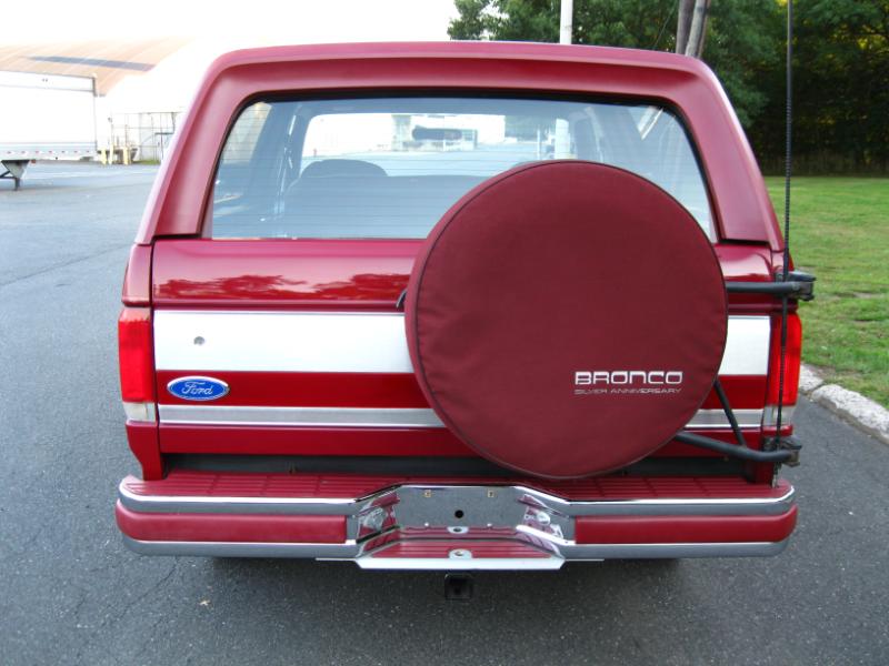 Red Ford Bronco rear view, spare tire cover says "Bronco Silver Anniversary"