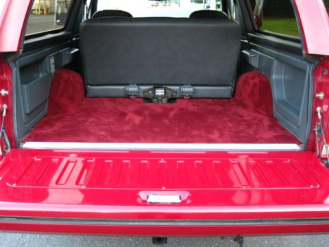 1994 Ford Bronco - Rear view of a red SUV's cargo area, showing custom red carpeting and a folded black seat.