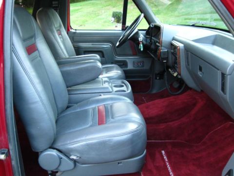 1994 Ford Bronco - The interior of a truck features gray leather seats and plush red carpeting.