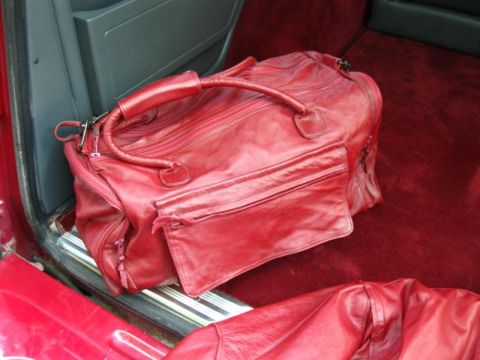1994 Ford Bronco - A red leather duffel bag rests on the red carpeted floor of a vehicle.