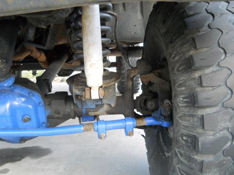 1992 Ford Bronco - Close-up view of the front suspension and steering linkage of a vehicle, showing aftermarket blue components.