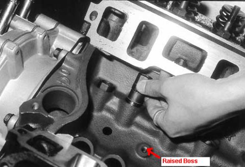 1990 Ford Bronco - Close-up of an engine block with a hand interacting with a component, highlighting a raised boss.