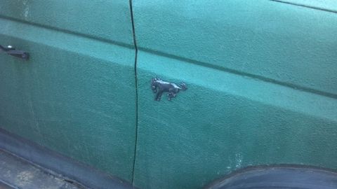 1986 Ford Bronco - Close-up of a green 1986 Ford Bronco door, showing the iconic running horse emblem.