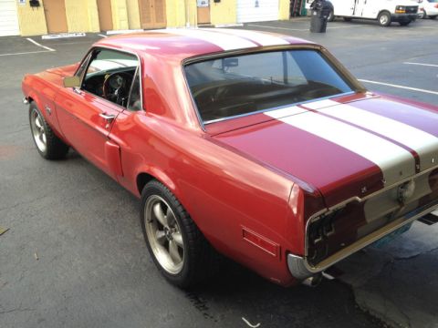 1968 Ford Mustang - 1968 Ford Mustang coupe with white racing stripes parked outdoors.