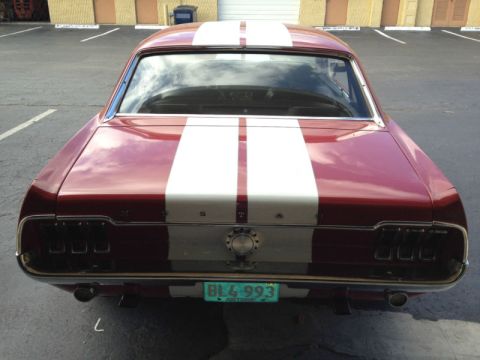 1968 Ford Mustang - The rear of a classic car, dual exhaust pipes and distinctive taillights, is parked in a lot.