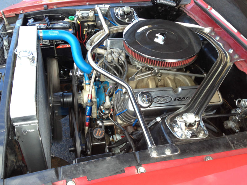 Red 1968 Ford Mustang engine bay with chrome air cleaner and blue hoses