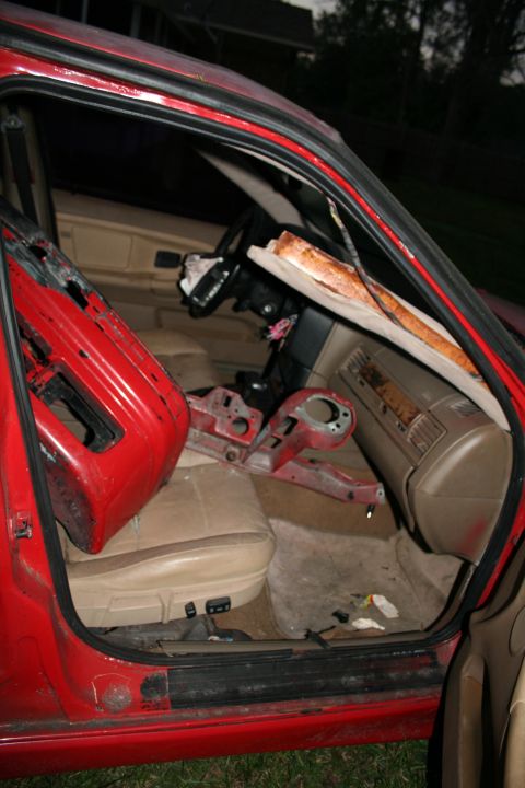 1996 BMW 3 Series - The interior of a red car is visible with the driver's side door open, revealing tan seats and a damaged dashboard.