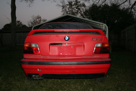 1996 BMW 3 Series - Rear view of a red 1996 BMW 328i with a spoiler and dual exhaust pipes.