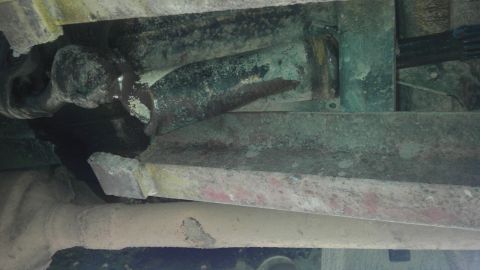 1989 Ford Bronco - Close-up of the undercarriage, focusing on rusted structural elements and mechanical parts.