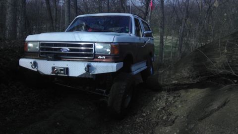 1989 Ford Bronco - This 1989 Ford Bronco navigates a challenging off-road trail with its distinctive two-tone paint and custom front bumper.