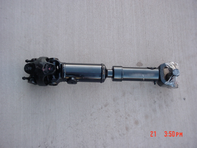 Black slip-yoke driveshaft with U-joints on a concrete floor, one joint taped