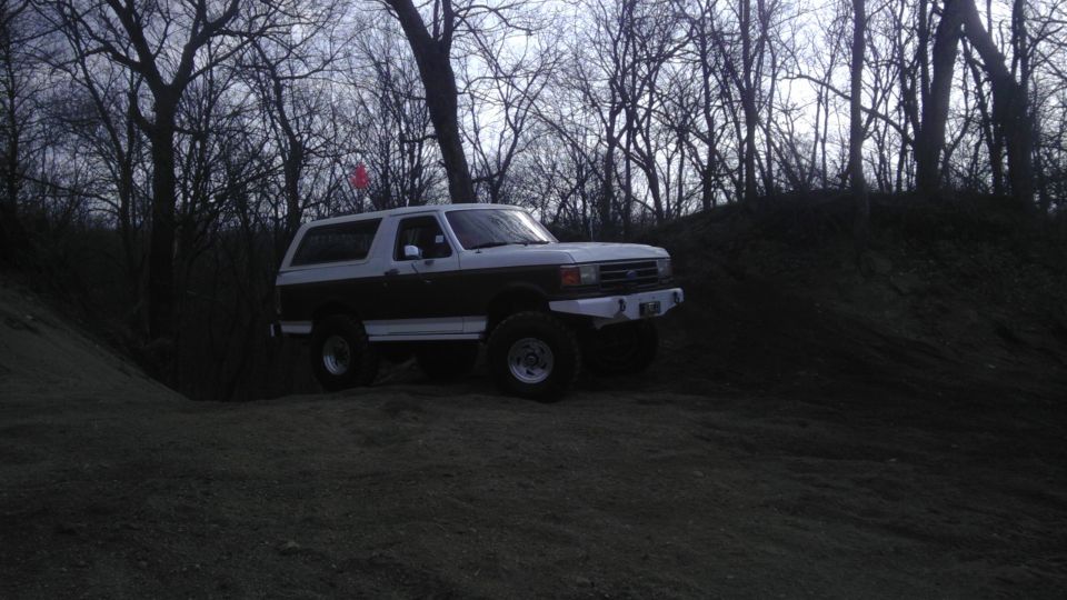 Two-tone Ford Bronco with aftermarket bumper on dirt hill