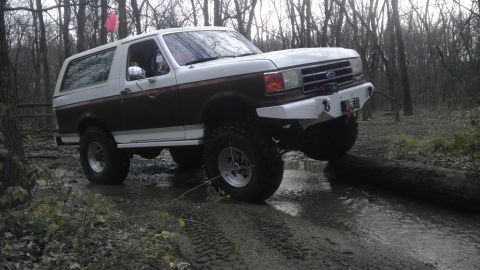 1989 Ford Bronco - This lifted 1989 Ford Bronco navigates a challenging off-road course through a wooded area.
