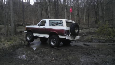 1989 Ford Bronco - This 1989 Ford Bronco is navigating a challenging muddy course in a wooded area.