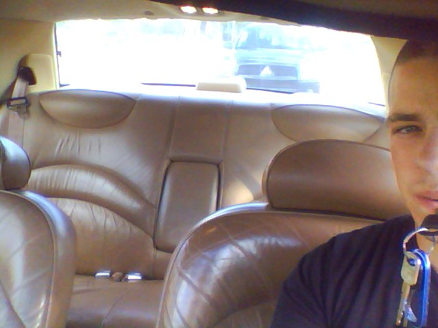 guy in car interior, tan leather seats, window shows another car outside