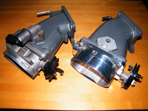 2004 Ford Crown Victoria - Two throttle bodies are shown on a wooden table, one a polished chrome intake.