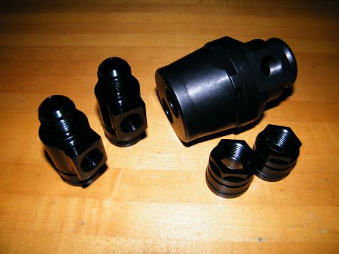 2004 Ford Crown Victoria - A collection of black anodized AN fittings and a large adapter are displayed on a wooden table.