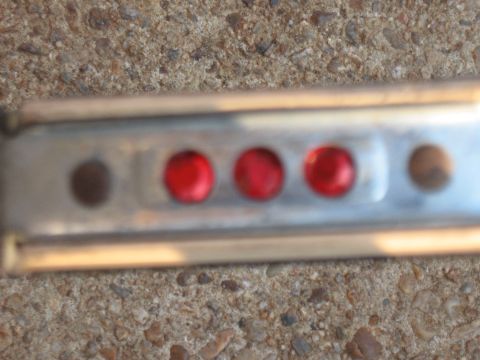 1994 Ford Bronco - Close-up of a metal strip with red lights, possibly part of a vehicle's exterior trim.